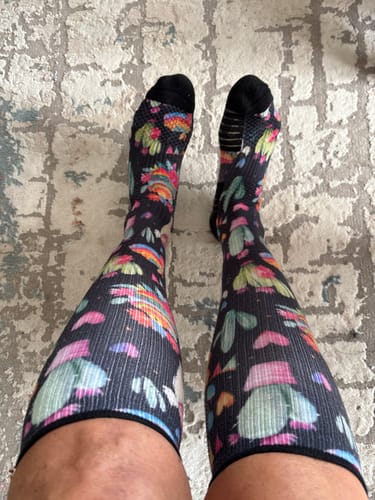 Reviewer showing their colorful Llama Love Compression Socks pulled up on their lower legs.