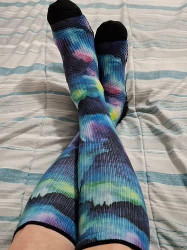 Reviewer's feet crossed, wearing the colorful Northern Lights Compression Socks with padded soles.