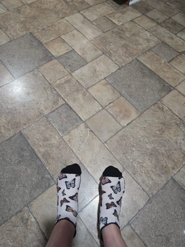 Customer's feet wearing white Summer Flutter Ankle Compression Socks with butterfly patterns on tiled floor